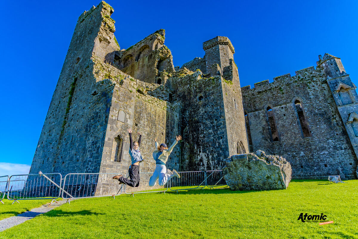 Atomic Trips travelers jumping for joy at the Rock of Cashel in Ireland